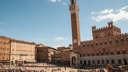 Busy plaza in Siena, Italy with prominent clock tower.